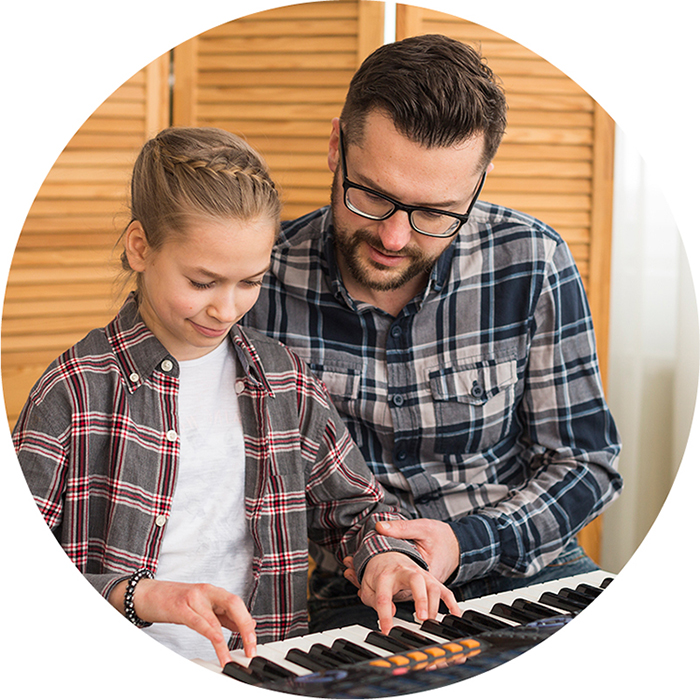 Musiklehrer übt mit Schülerin auf dem Keyboard
